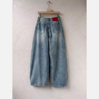 Calças de ganga GRINE wide leg em azul claro com lavagem vintage e etiqueta vermelha na cintura, vista traseira.