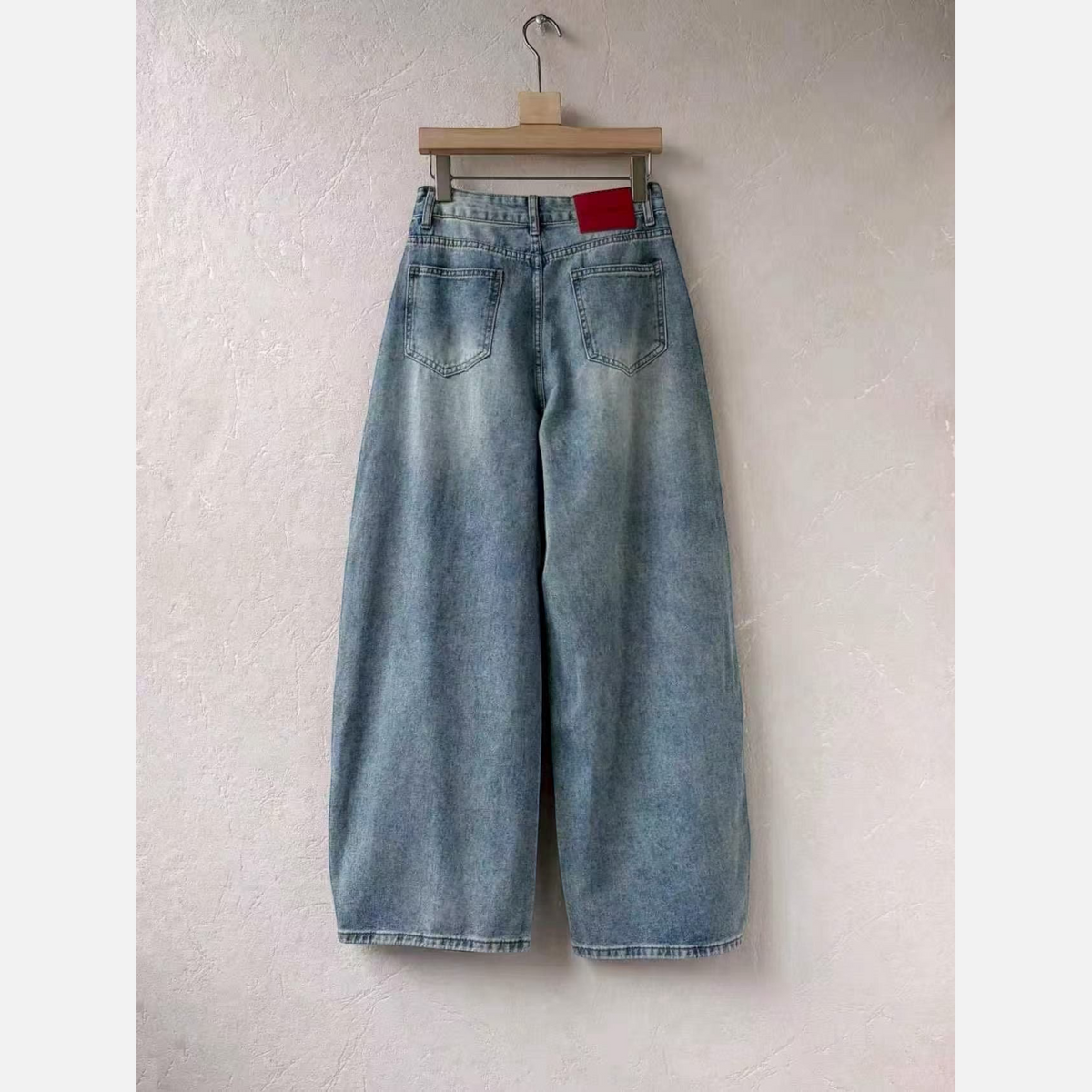 Calças de ganga GRINE wide leg em azul claro com lavagem vintage e etiqueta vermelha na cintura, vista traseira.