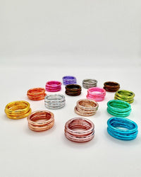 Conjunto de anéis GRINE flexíveis e impermeáveis em várias cores com folhas de ouro, simbolizando sorte e amor.