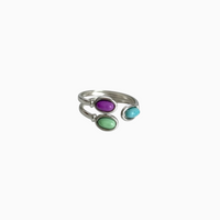 Anel GRINE ajustável em aço inoxidável com três pedras ovais coloridas em tons de roxo, verde e azul turquesa.