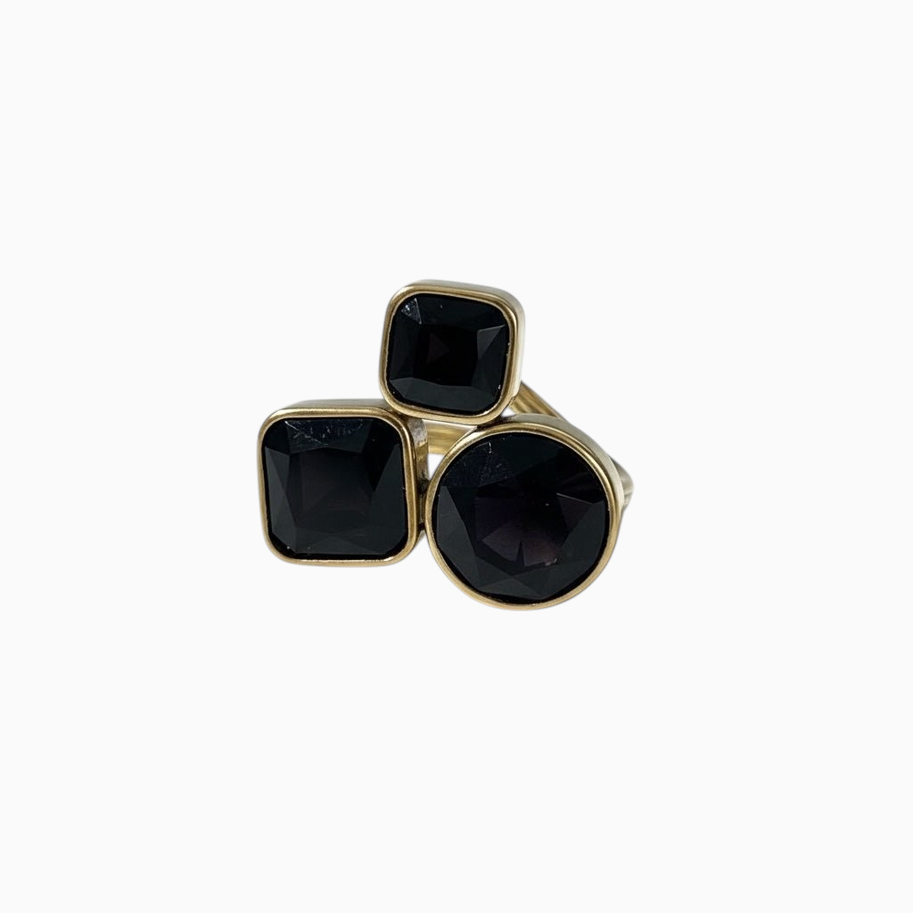 Anel GRINE em aço inoxidável dourado com três pedras pretas lapidadas em design sofisticado e ajustável.