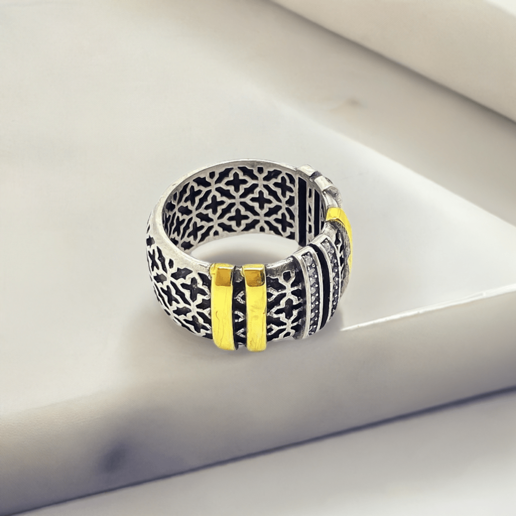 Anel GRINE com design arabesco detalhado em prata envelhecida e detalhes em ouro, estilo contemporâneo e sofisticado.