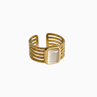 Anel GRINE largo ajustável em aço inoxidável dourado com pedra retangular clara e design de bandas múltiplas.