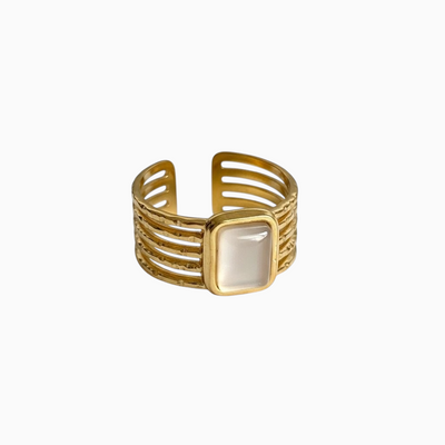 Anel GRINE largo ajustável em aço inoxidável dourado com pedra retangular clara e design de bandas múltiplas.