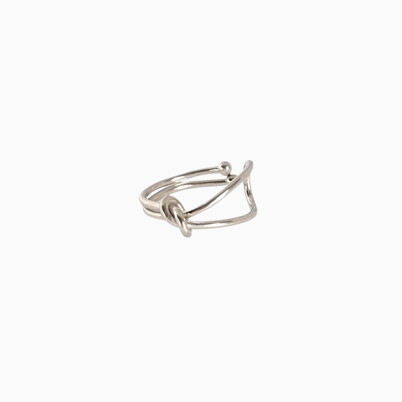 Anel GRINE com design de nó minimalista em acabamento prateado, elegante e sofisticado sobre fundo branco.