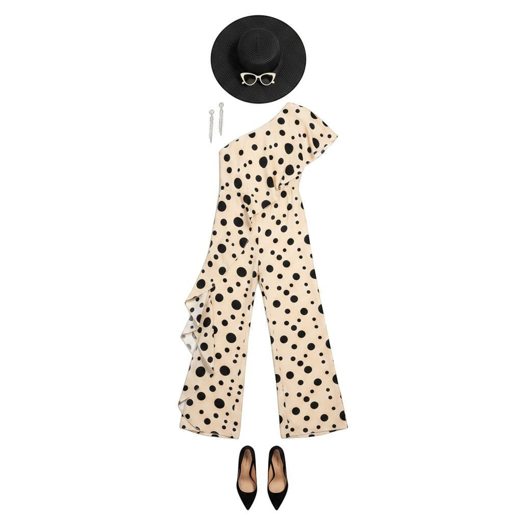 GRINE beige one-shoulder jumpsuit with black polka dots, elastic waist, and wide legs. Model wears a black hat and heels.