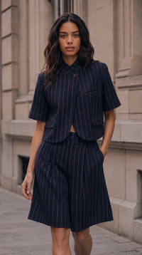 Modelo veste bermudas de alfaiataria GRINE com padrão risca de giz, cintura subida e corte largo em ambiente urbano.