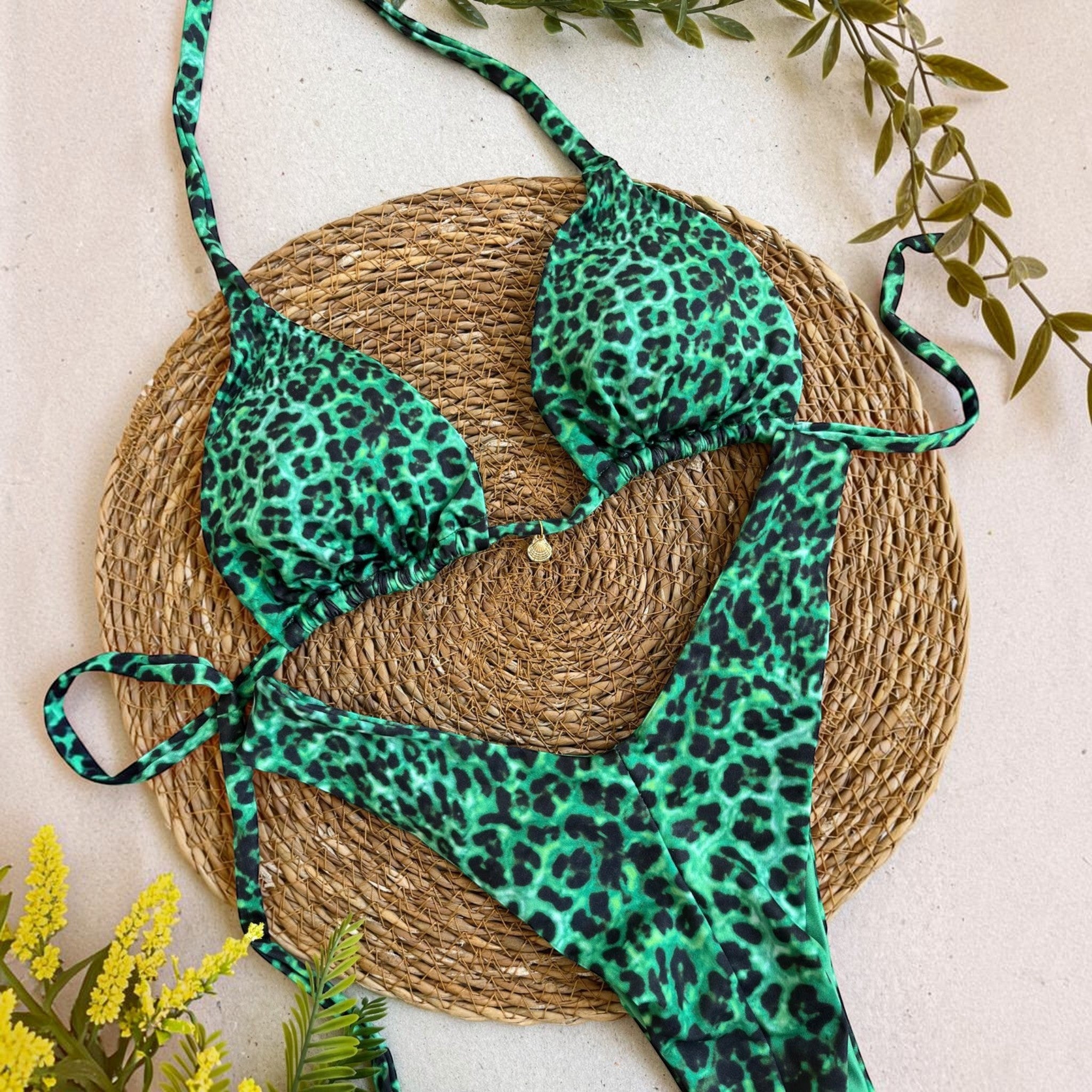 Biquíni GRINE cortininha e asa delta com estampa animal print em tons de verde esmeralda e preto sobre base de palha.