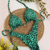 Biquíni GRINE cortininha e asa delta com estampa animal print em tons de verde esmeralda e preto sobre base de palha.