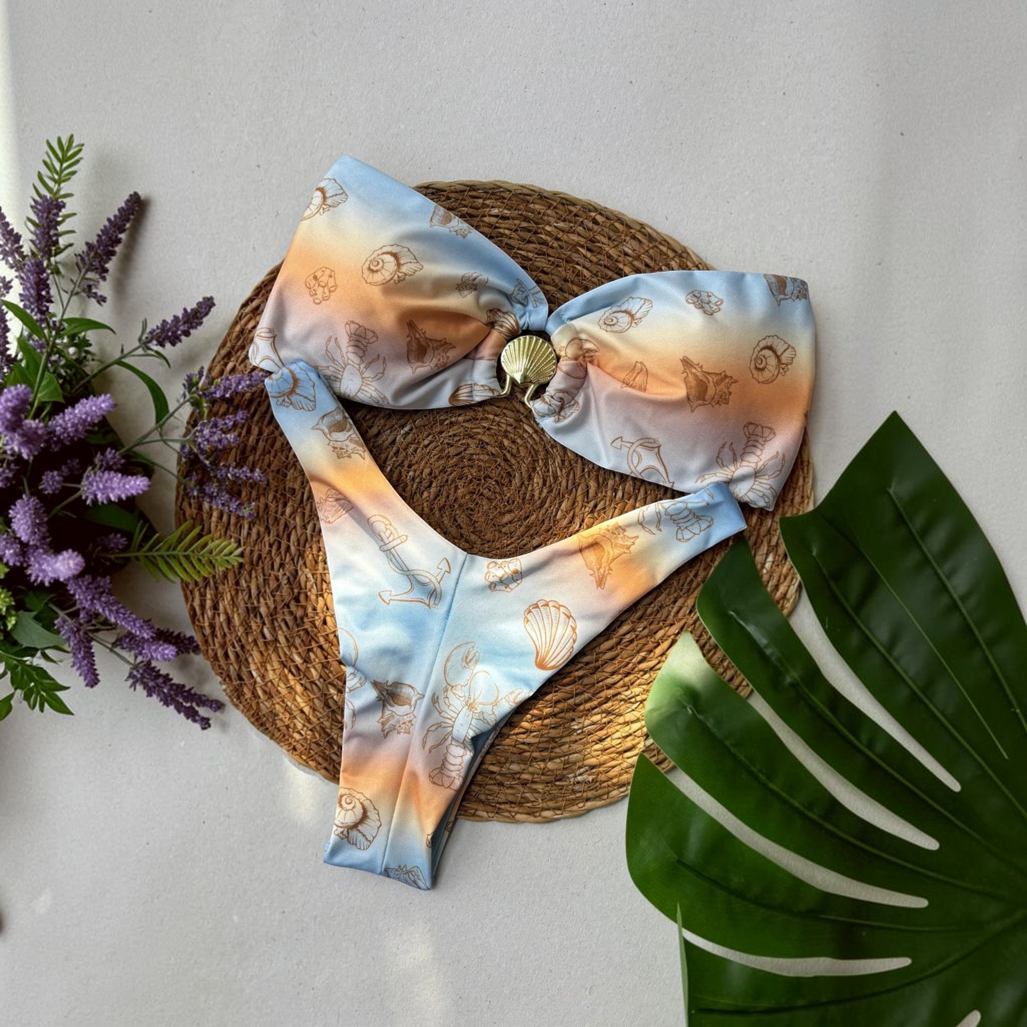 Biquíni GRINE modelo Cancún com estampa degradé azul e amarelo, motivos marinhos e detalhe de concha no busto caicai.
