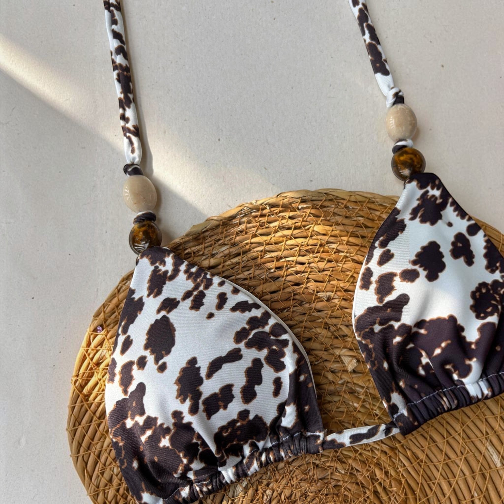 Biquíni GRINE modelo cortininha com estampa cow print, detalhes de contas nas alças sobre base de palha.