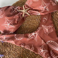 Biquíni GRINE Sardenha tomara que caia castanho com estampa de conchas e estrelas-do-mar e detalhe de estrela dourada.