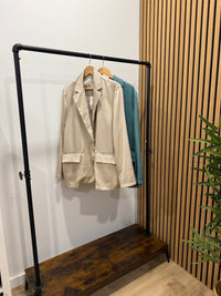 Blazer oversize acetinado GRINE bege com corte fluido, um botão e bolsos frontais, pendurado num cabide