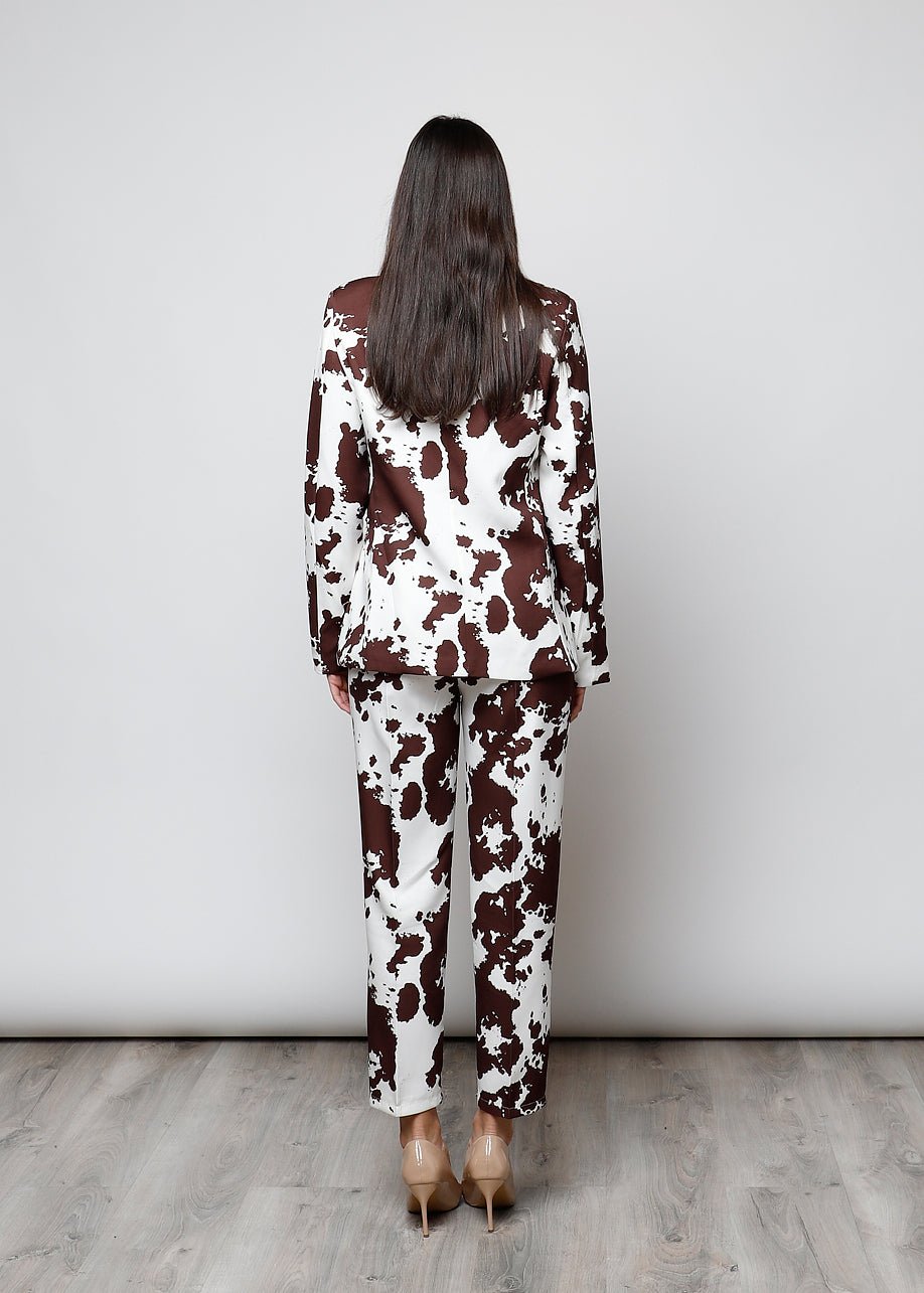 Vista traseira de modelo com blazer e calças GRINE com estampa cow castanha e branca, corte estruturado e forrado.
