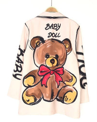 Blazer oversized bege GRINE com estampa de urso castanho e laço vermelho nas costas e texto Baby Doll