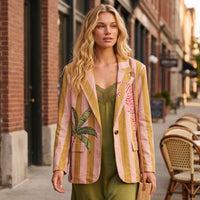 Modelo veste blazer oversized GRINE de camurça sintética com riscas, estampado de tigre rosa e palmeira em ambiente urbano