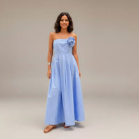GRINE light blue cotton strapless maxi dress with a removable flower detail and elasticated bust. Model wears sunglasses and sandals.