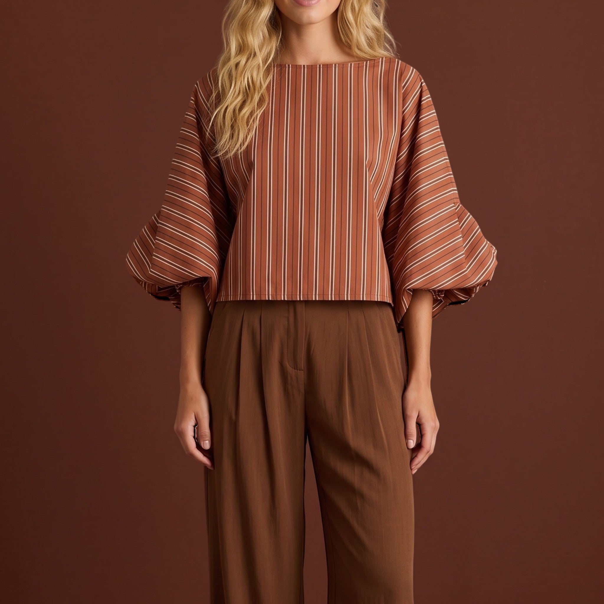 Modelo veste blusa GRINE curta listrada em tons terrosos com mangas bufantes volumosas e punhos franzidos