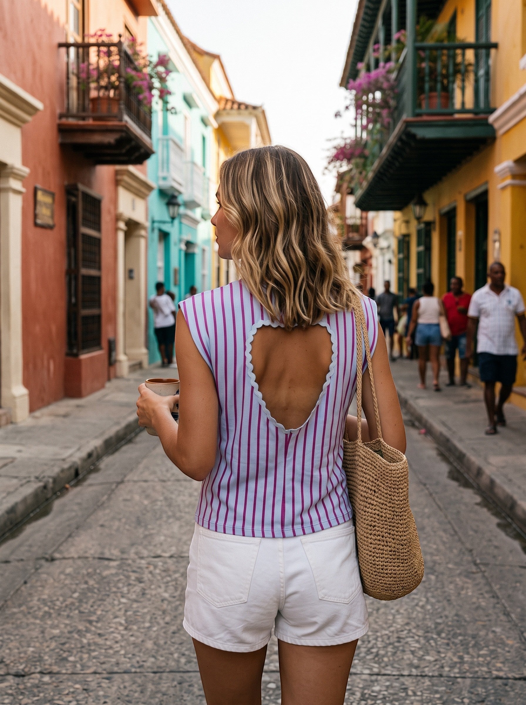 Blusa GRINE às riscas com detalhe de coração aberto nas costas, em algodão, usada por mulher numa rua colorida.