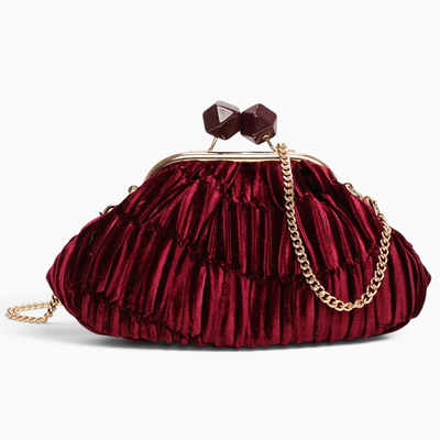 Bolsa de festa GRINE em veludo bordeaux com textura plissada, fecho de molas decorativo e alça de corrente dourada.
