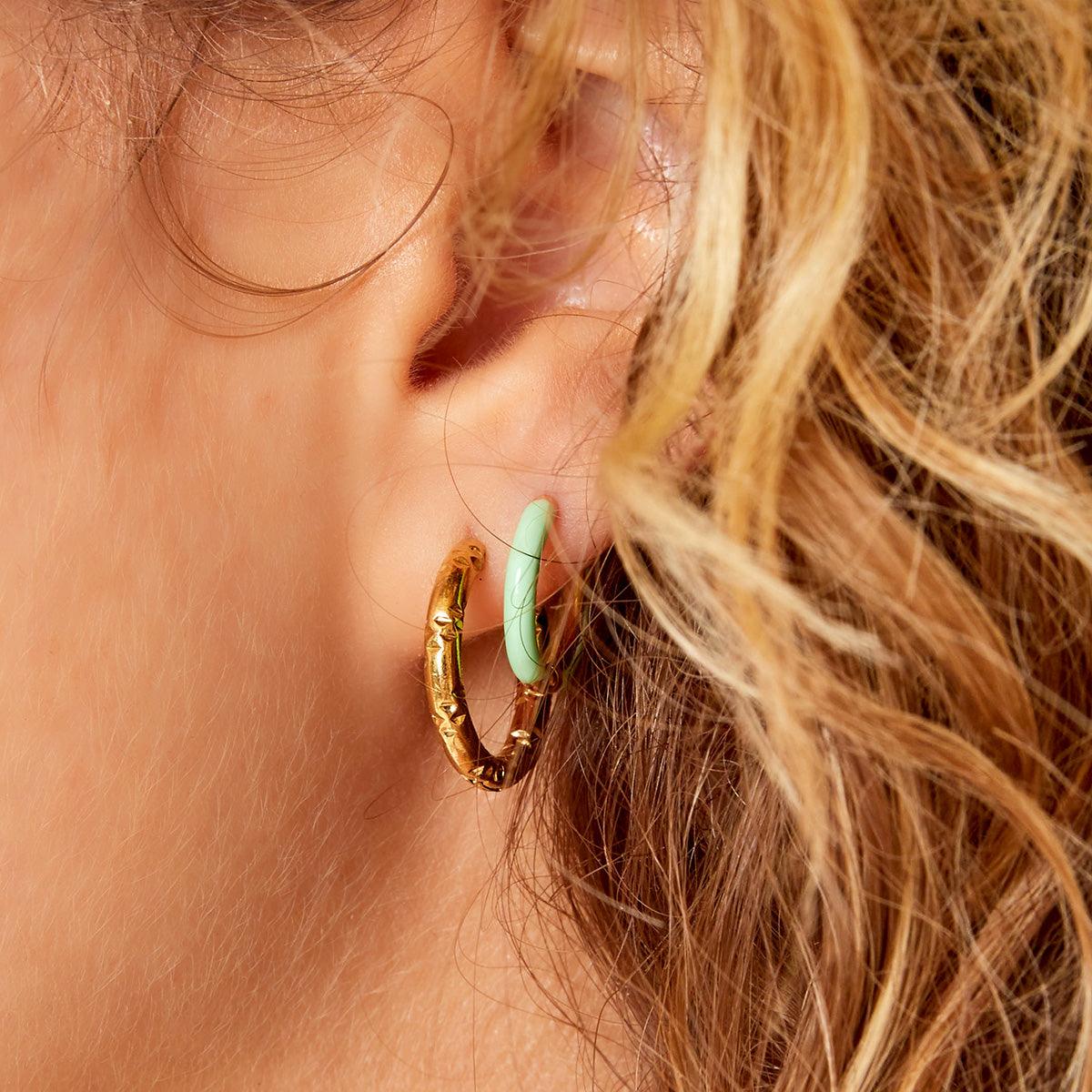 Brincos argolas GRINE em aço inoxidável dourado com detalhe em esmalte verde menta, design delicado e sofisticado.