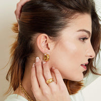 Modelo usando brincos GRINE Diamond Flowers em aço inoxidável dourado com flores de zircónias e anel a condizer