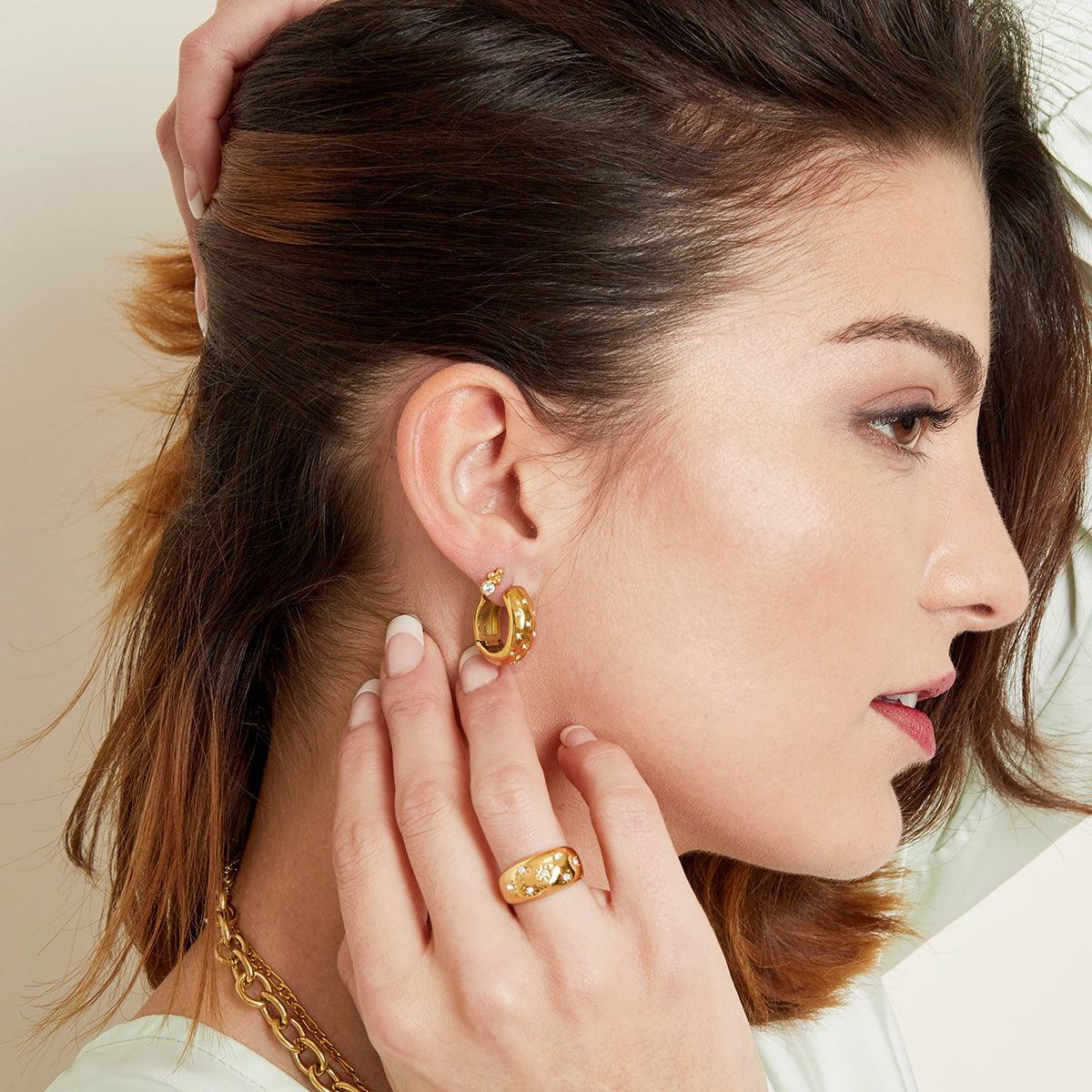 Modelo usando brincos GRINE Diamond Flowers em aço inoxidável dourado com flores de zircónias e anel a condizer
