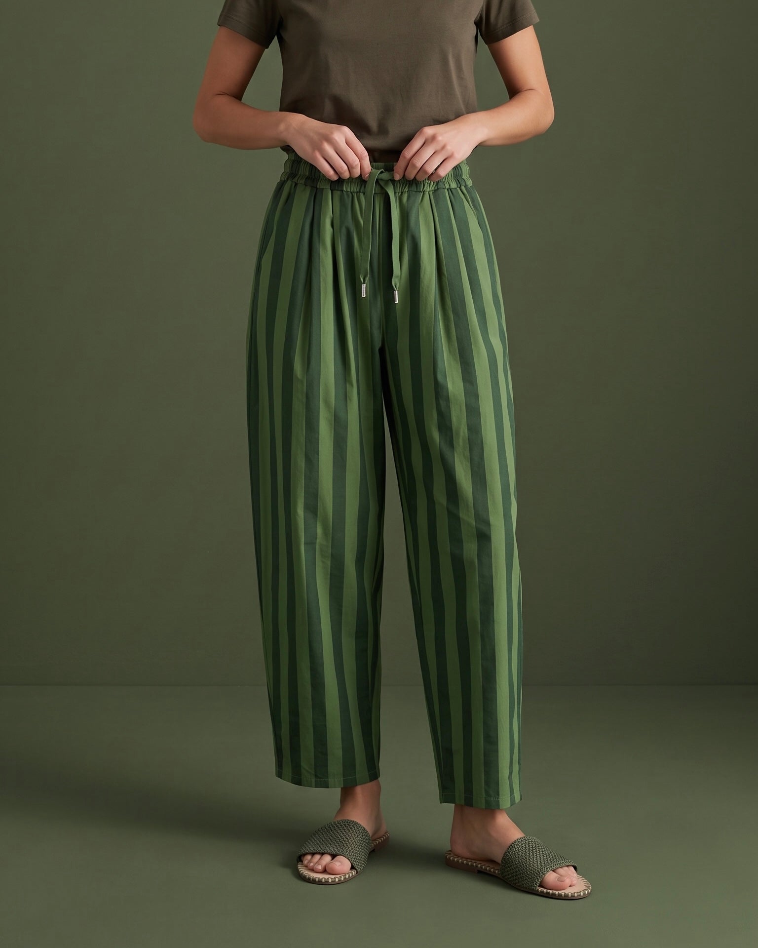Calças baggy GRINE de algodão com riscas verticais verdes, cintura subida elástica e pregas frontais.