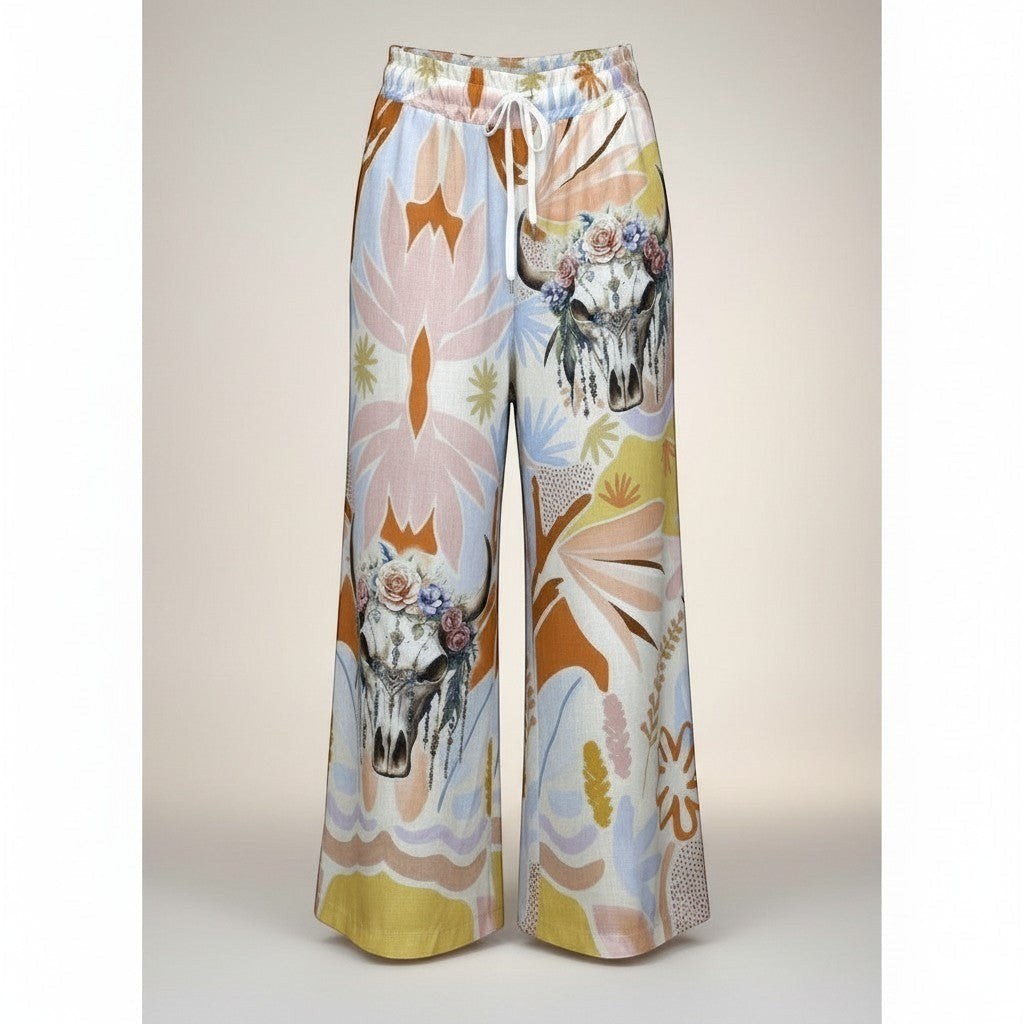Calças Carmen GRINE de perna larga com estampado artístico tropical, caveiras florais e cintura elástica. Tons suaves e quentes.