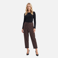 Modelo veste calças chino castanhas GRINE com cós cruzado assimétrico, botões prateados e corte fluido de alfaiataria.