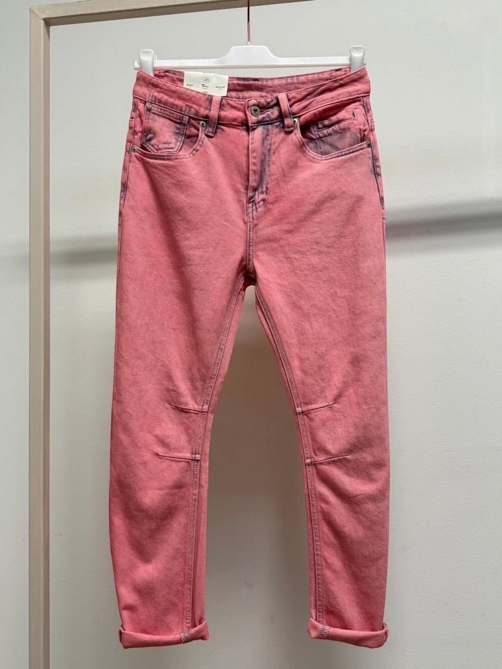 Calças de ganga GRINE modelo Kelly em rosa com efeito lavado, corte baggy ankle e bainhas dobradas num cabide