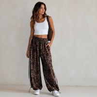 Modelo veste calças jogger GRINE oversized com padrão animal print, riscas laterais brancas e bainhas ajustáveis.