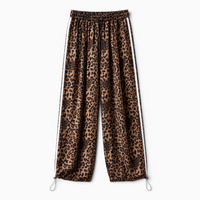 Calças jogger GRINE oversized com padrão animal print, riscas laterais brancas e bainhas ajustáveis com cordão.