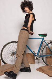 Modelo veste calças jogger fluidas taupe da GRINE com cintura elástica, combinadas com top preto e botas robustas.