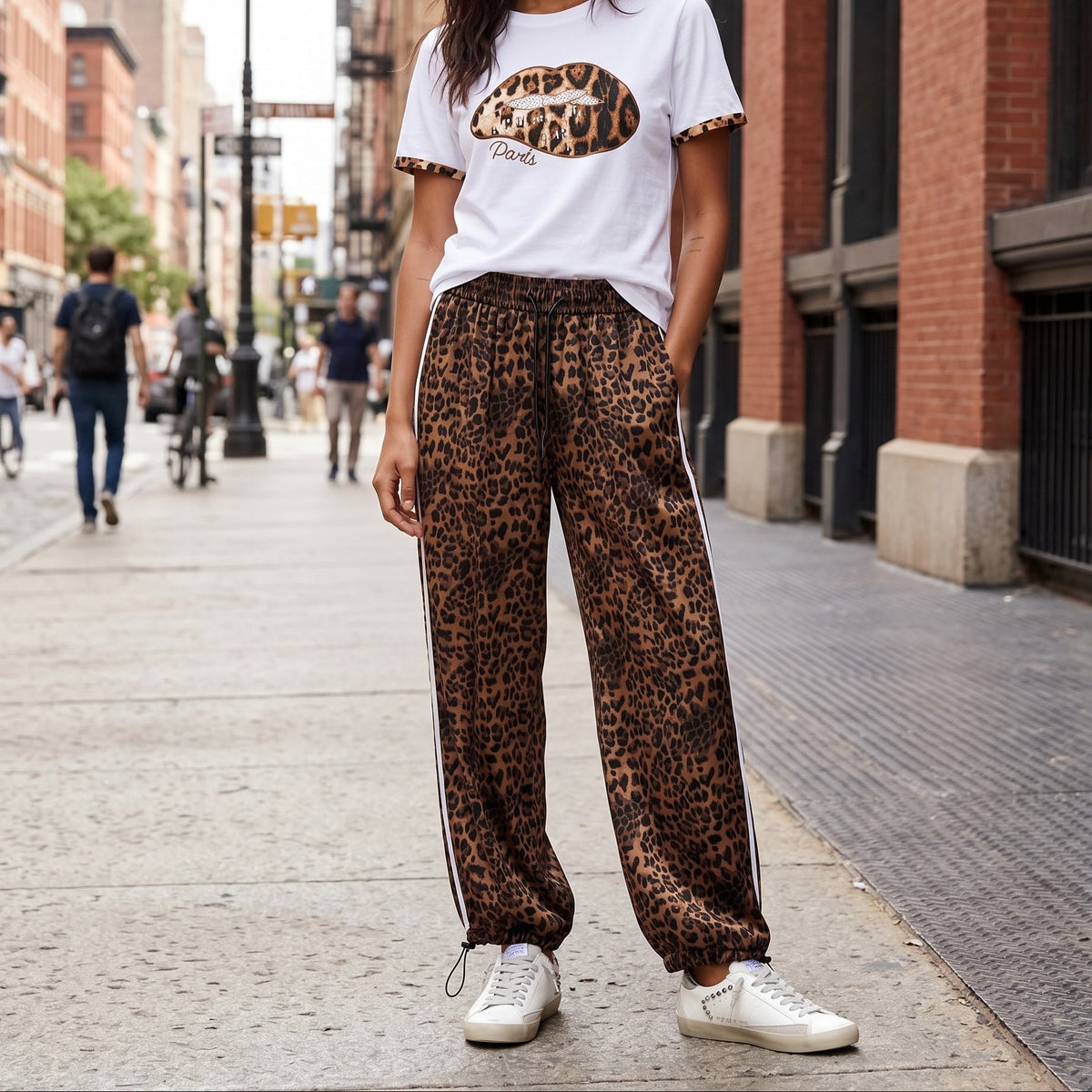 Modelo veste calças jogger GRINE oversized com padrão leopardo, riscas laterais brancas e bainhas ajustáveis na rua.