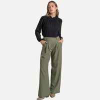 Modelo veste calças pantalona fluidas GRINE em tom cinzento com corte largo, cintura subida e bolsos laterais.