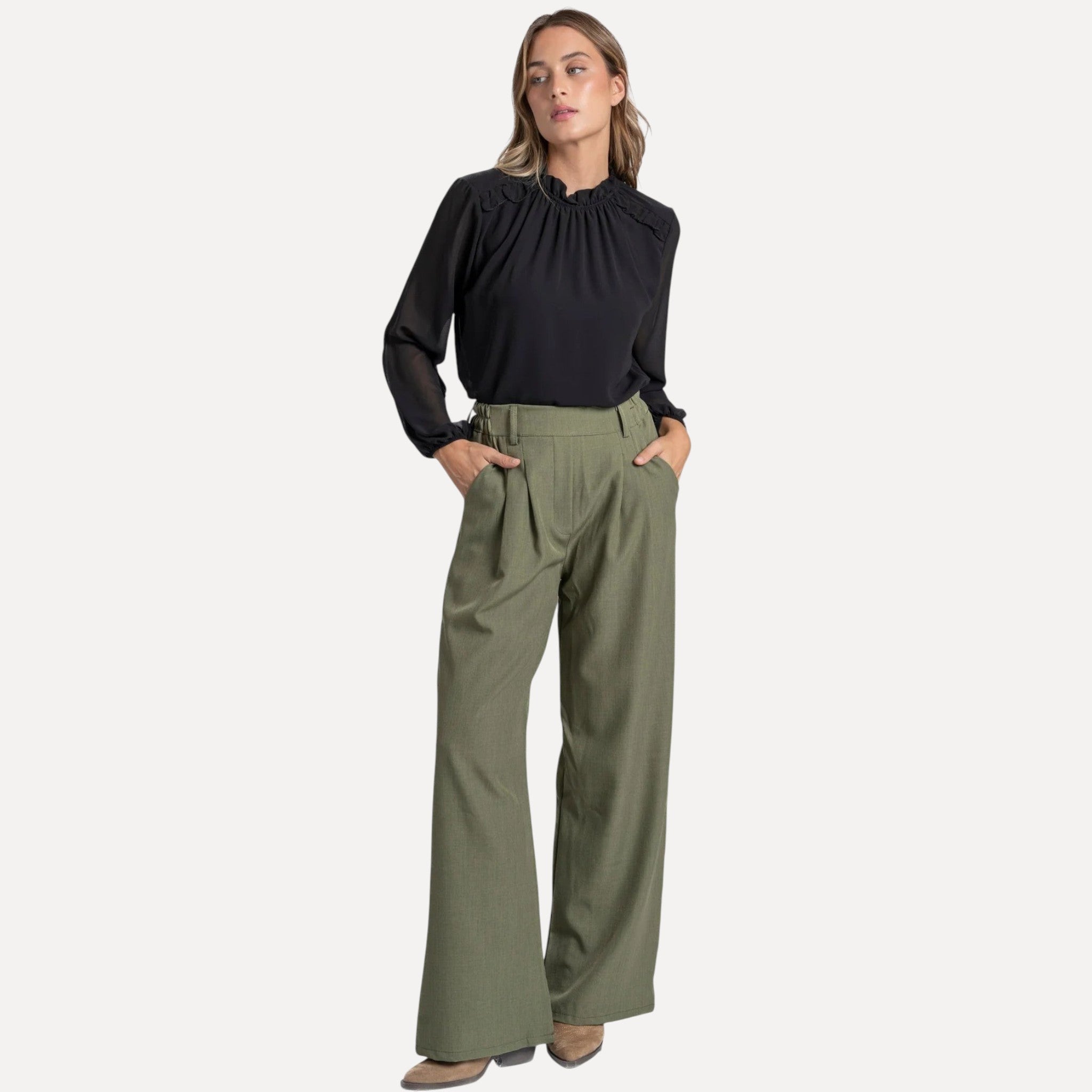 Modelo veste calças pantalona fluidas GRINE em tom cinzento com corte largo, cintura subida e bolsos laterais.