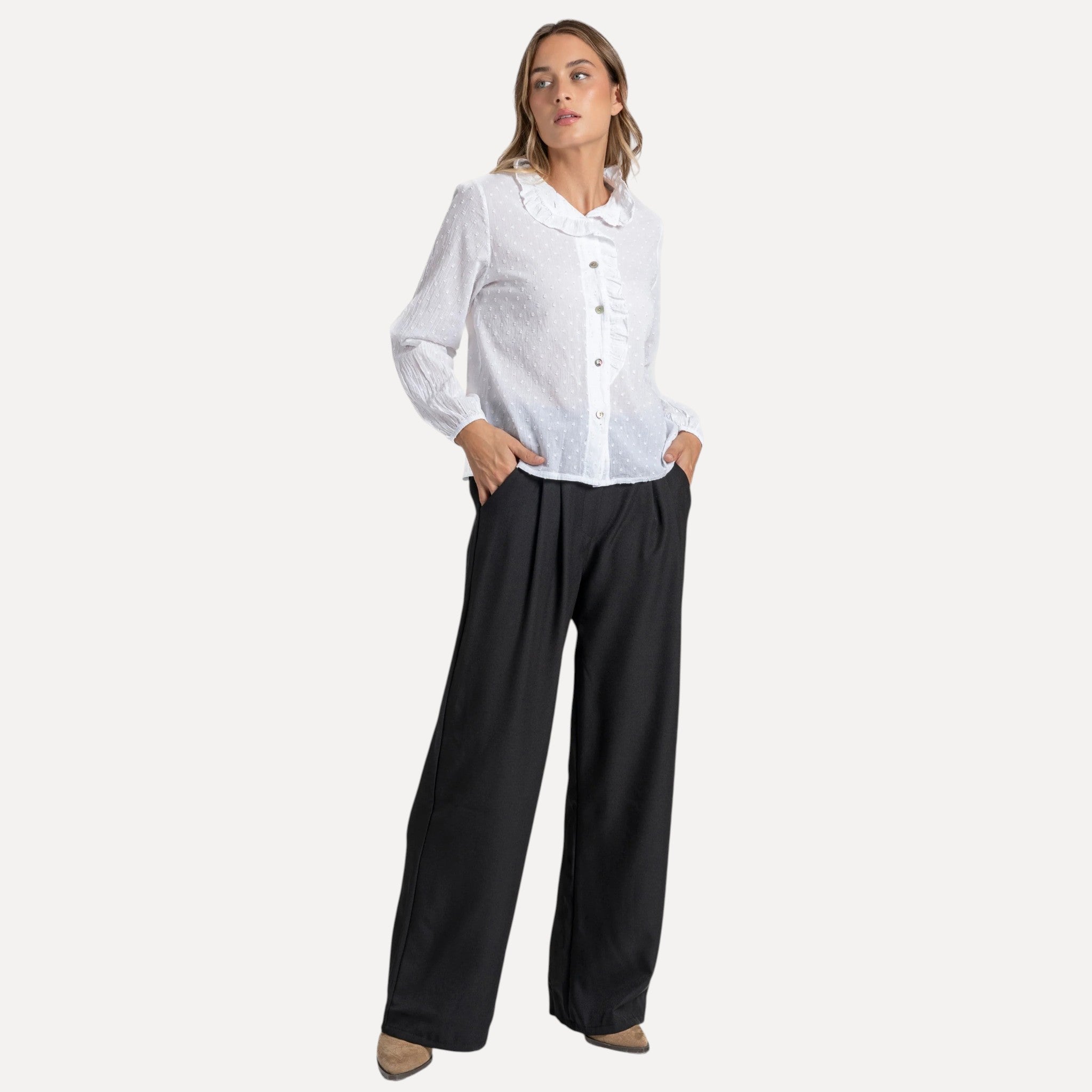 Modelo GRINE veste calças pantalona pretas fluidas de corte largo com blusa branca, estilo elegante e confortável.