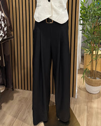 Calças pantalonas pretas GRINE de perna larga com cintura elástica e bolsos, exibidas em manequim.