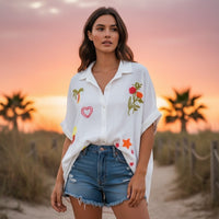 GRINE Camisa branca de algodão com bordados coloridos de palmeira, coração, sereia e flores. Corte oversize.