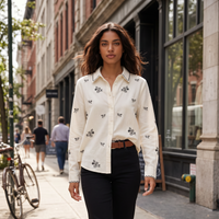 Modelo veste camisa branca GRINE em algodão com delicados bordados pretos em ambiente urbano