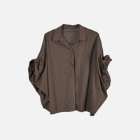 Camisa GRINE oversized castanha com corte fluido, mangas morcego volumosas e punhos drapeados em tecido leve.