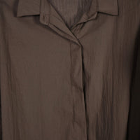 Detalhe da gola e carcela oculta da camisa fluida oversized castanha da GRINE em tecido leve de algodão.