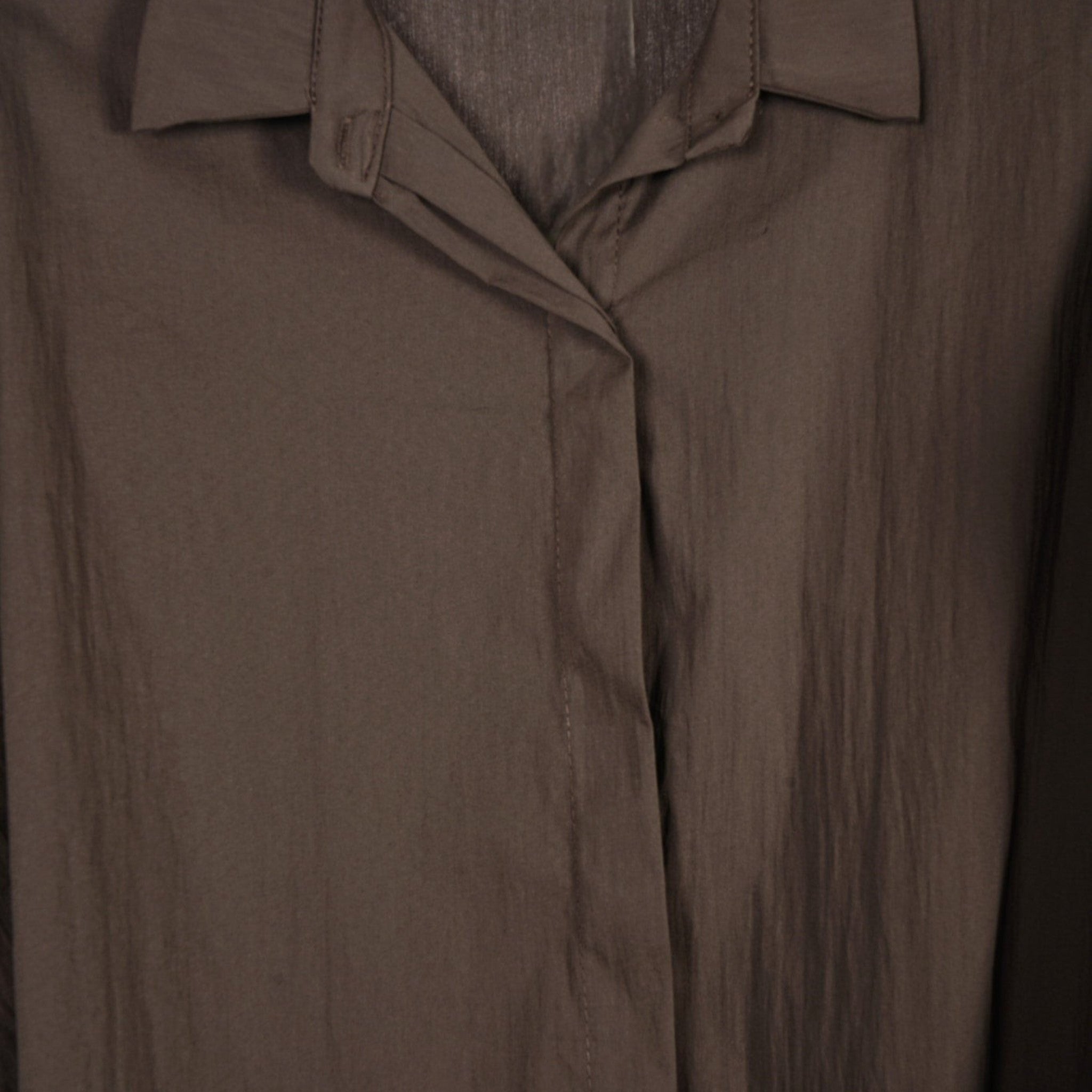 Detalhe da gola e carcela oculta da camisa fluida oversized castanha da GRINE em tecido leve de algodão.