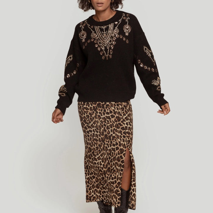 Camisola de malha preta GRINE com lantejoulas douradas, gola redonda e manga comprida, usada com saia leopardo.