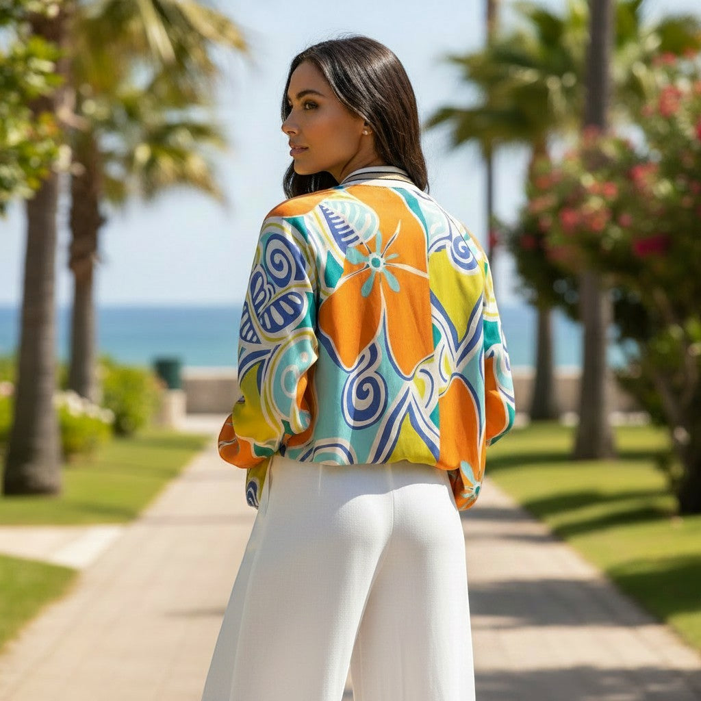 Casaco bomber GRINE em viscose com estampado floral vibrante em laranja, azul e verde. Gola, punhos e cós com detalhes dourados.