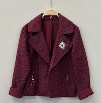 Casaco curto GRINE em tecido texturado bordeaux com gola de lapela, bolsos falsos e pregadeira decorativa dourada.