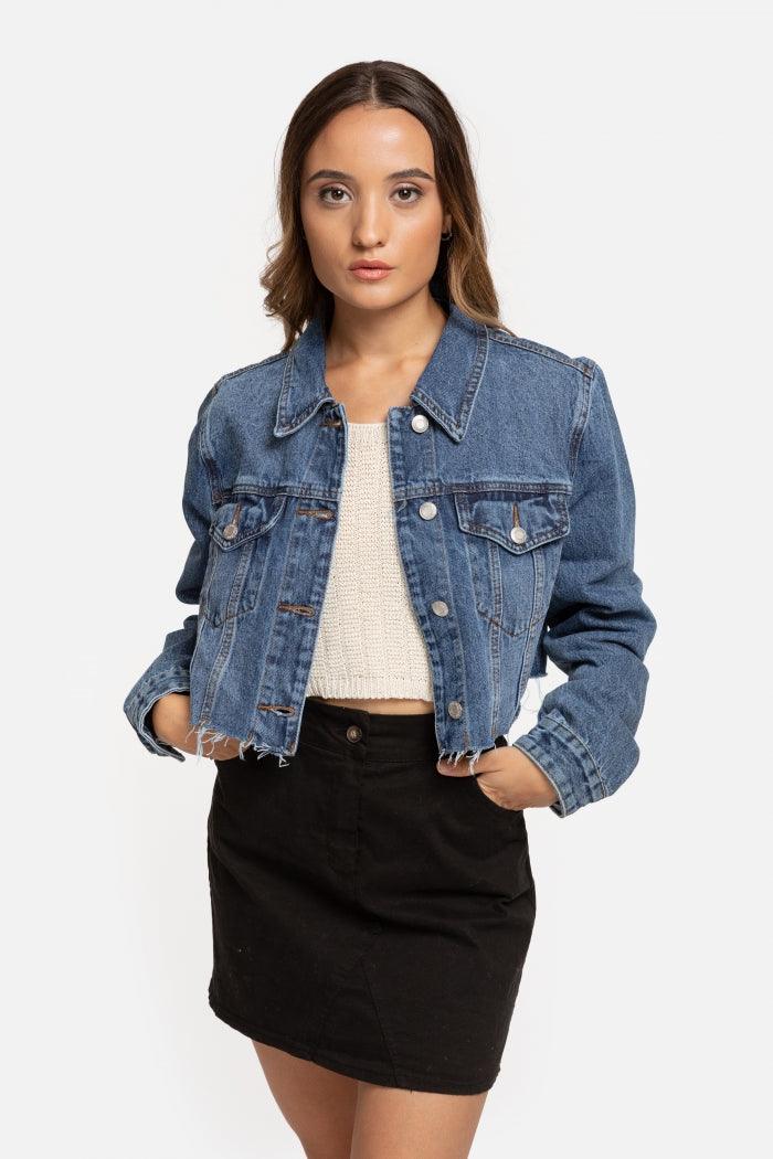 Modelo veste casaco de ganga curto azul da GRINE com gola, bolsos frontais e bainha desfiada em fundo branco