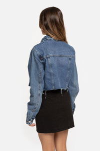 Casaco de ganga curto GRINE azul com corte reto, gola de camisa e bainha desfiada, visto de costas numa modelo.
