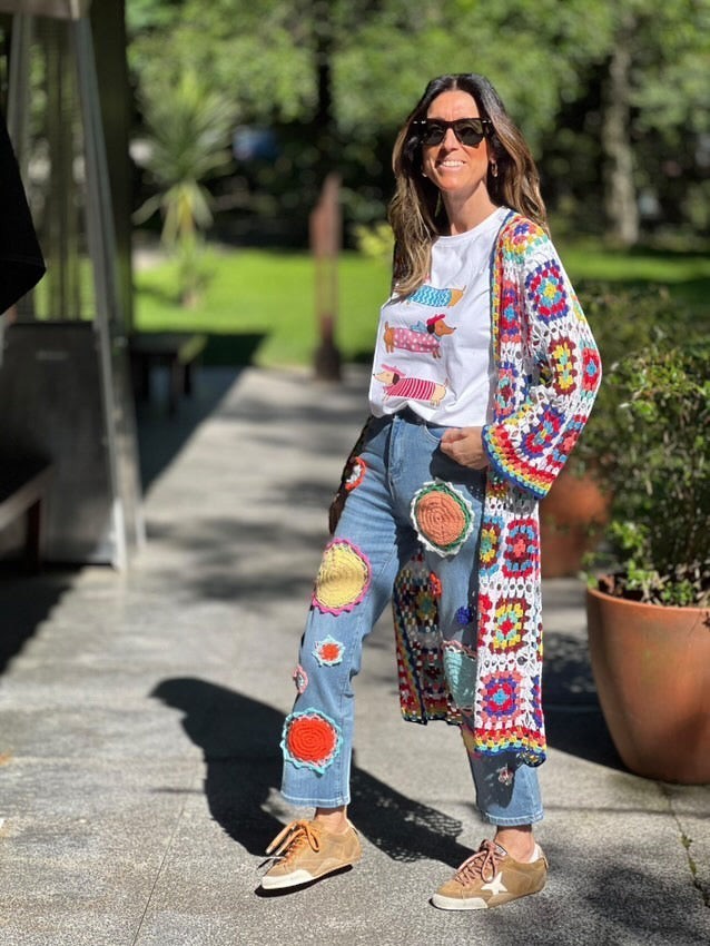 Casaco/kimono comprido de crochet GRINE com padrão de quadrados coloridos e ponto aberto, usado por uma mulher com calças de ganga decoradas.